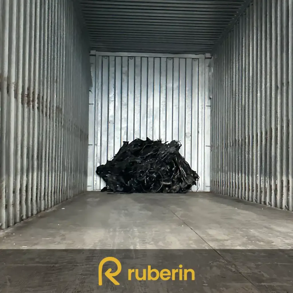 Minimal load of black rubber scrap placed at the end of an empty shipping container for transport.
