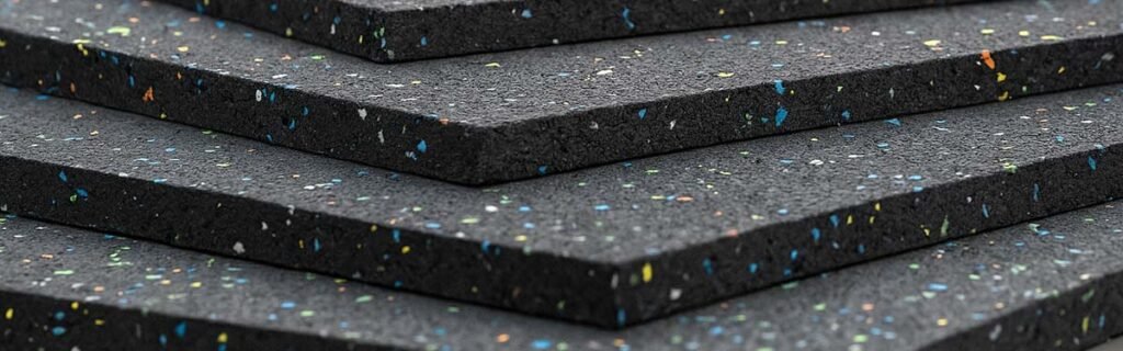 Stacked recycled rubber sheets with colorful speckles used in steel friction applications and industrial scrap processing.