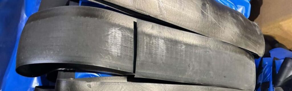 Prepared strips of raw rubber compound stacked for further processing in industrial rubber manufacturing.